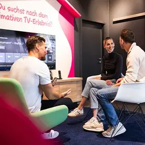 Drei Personen im Büro sprechen über Smart-TV-Streaming am Bildschirm