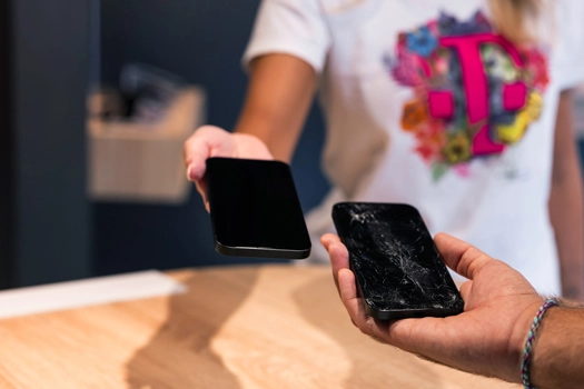 Handy-Reparatur im Shop: Kunde übergibt Smartphone, defektes Display sichtbar